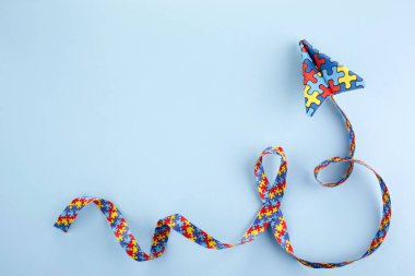 Otizm farkındalığı gün veya ay. Mavi arkaplanda otizm farkındalığı bulmaca kurdelesiyle origami tarzında kağıt düzlem.