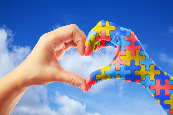 Día Mundial del Autismo, concepto de cuidado de la salud mental con patrón de rompecabezas en las manos en forma de corazón . — Foto de Stock