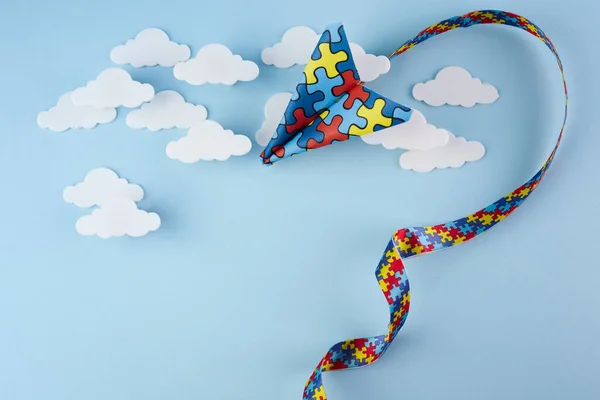 Świadomość autyzmu dzień lub miesiąc. Płaszczyzna papieru w stylu origami z autyzmem puzzle wstążka na niebieskim tle. — Zdjęcie stockowe