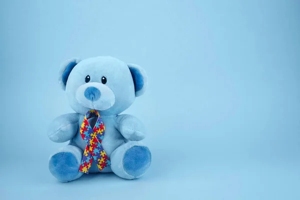 World Autism Awareness, Konzept mit Teddybär, der Puzzle oder Stichsägeband auf blauem Hintergrund hält — Stockfoto