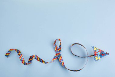 Otizm farkındalığı gün veya ay. Mavi arkaplanda otizm farkındalığı bulmaca kurdelesiyle origami tarzında kağıt düzlem.