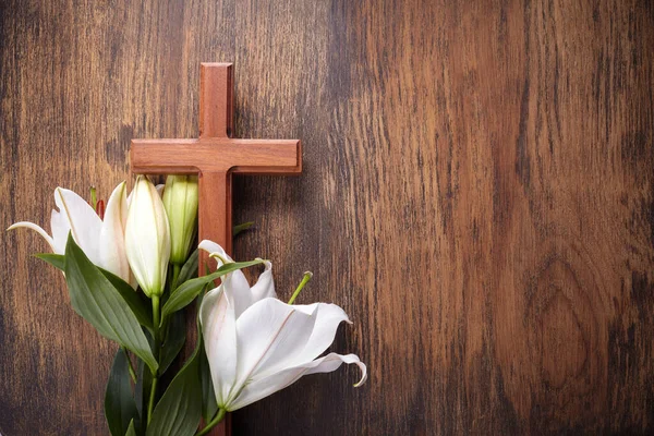 Dřevěný kříž a bílá lilie na venkovském stole — Stock fotografie