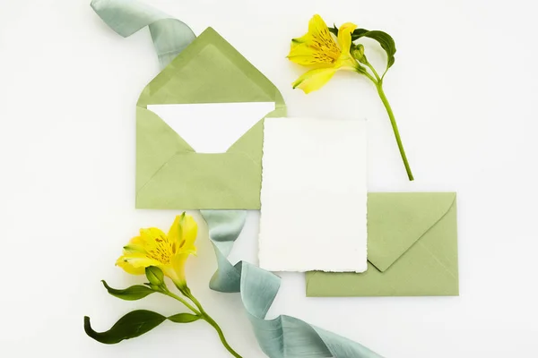 Tarjeta de felicitación blanca en blanco con sobre y flores de fondo blanco. Vista superior. Prepárate. —  Fotos de Stock