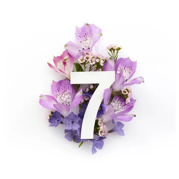 Kreatywny układ z kolorowymi kwiatami i numerem siedem. Leżeć płasko. Widok z góry. — Zdjęcie stockowe