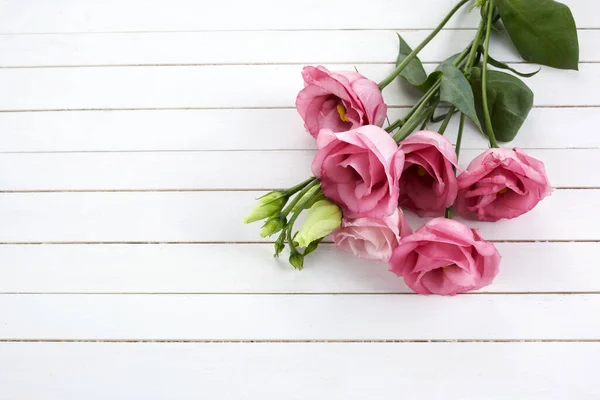 Różowe kwiaty eustoma na drewnianym tle w stylu vintage. Romantyczne tło wesela. Widok z góry. — Zdjęcie stockowe
