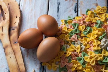 Kırsal masada yumurta ve biberin yanında renkli kuru erişte.