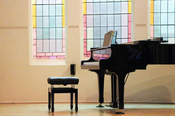 教堂里美丽的彩色玻璃窗户映照在闪亮的黑色大钢琴上 — 图库照片