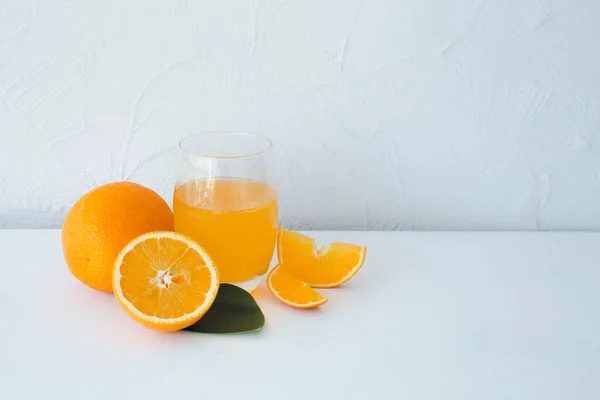 Jus d'orange frais aux oranges et tranches d'orange sur table blanche Image En Vente