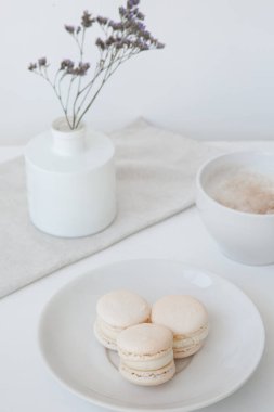 Makarnalar, sabah kahvesi. Arka planda bulanık vazo ve mavi çiçekler var.