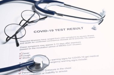 COVID-19 veya yeni koronavirüs salgını için pozitif test sonuçları. Stetoskop ve yeni koronavirüs testi doktor masasında sonuç veriyor.