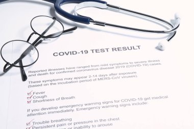 COVID-19 veya yeni koronavirüs salgını için pozitif test sonuçları. Stetoskop ve yeni koronavirüs testi doktor masasında sonuç veriyor.