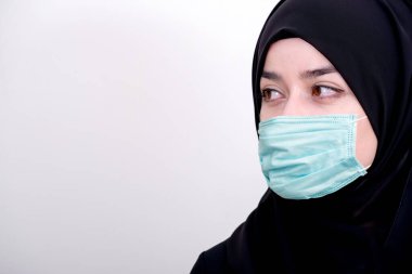 Korunmak için cerrahi maske takan Müslüman bir kız. Başörtülü kadın koronavirüs veya COVID-19 salgını veya salgın için maske takar.