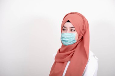 Korunmak için cerrahi maske takan Müslüman bir kız. Başörtülü kadın koronavirüs veya COVID-19 salgını veya salgın için maske takar.