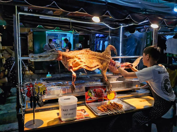 Khao San Road, Bangkok / Tayland - Şubat 2020: Tayland sokak yiyecek satıcısı barbeküde timsah pişiriyor