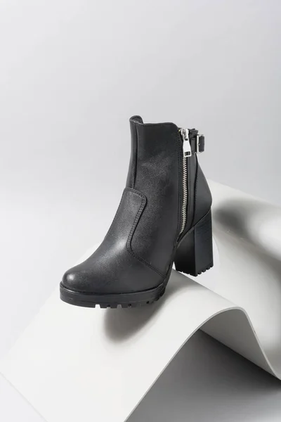 グレーのオブジェクトと異なる色でペイントする灰色の背景に黒の女性の足首ブーツ 靴カタログ — ストック写真
