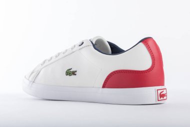 Lacoste beyaz spor ayakkabıları ve beyaz arka planda kırmızı detaylar katalogda tanıtılacak.