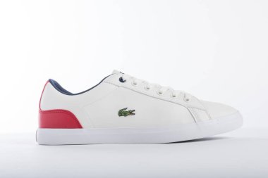 Lacoste beyaz spor ayakkabıları ve beyaz arka planda kırmızı detaylar katalogda tanıtılacak.