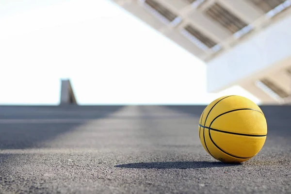 Yellow basketball on an asphalt ground.