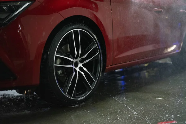Wheel of a red car in the rain.