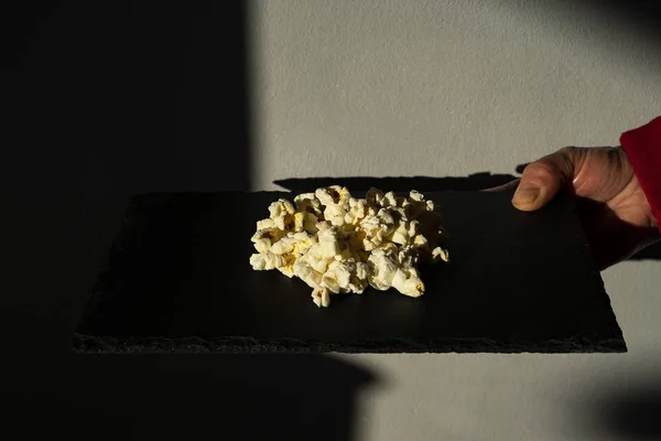 Gourmet popcorn on top of a black plate.