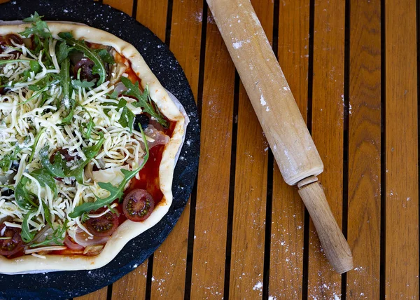 Vegetarian and vegetable pizza next to a wooden rolling pin. Vegetable pizza concept.