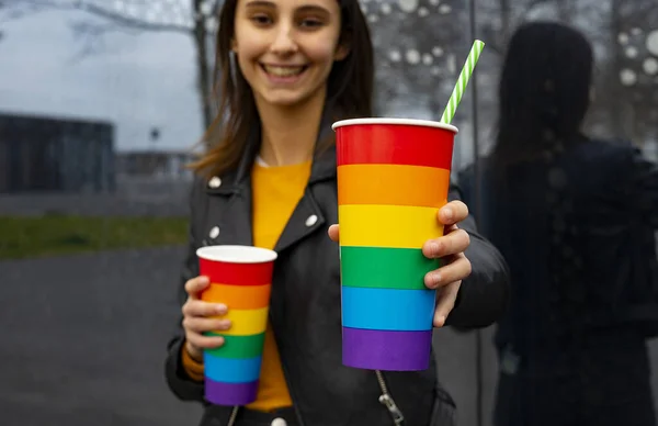 Woman offering a glass of soda at a party. Pride party concept.