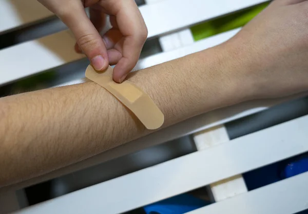 Hand putting band-aid on a wound on the arm. Band aid concept.