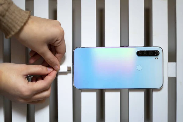 Hand connecting the mobile charger to the mobile phone. Charger and mobile concept.