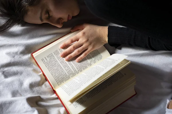 Woman sleeping next to an open book. Sleeping concept with books.