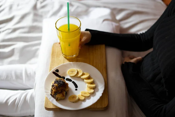 Woman having breakfast in bed in the morning. Breakfast in bed concept.