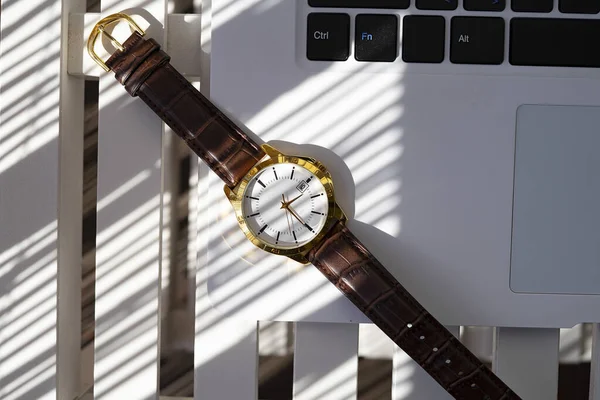 Gold and quartz watch on top of a laptop. Watch concept.