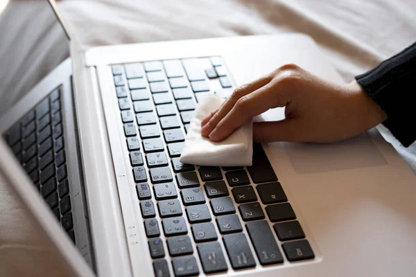 Hand disinfecting the laptop keyboard with a wipe. Disinfectant concept.