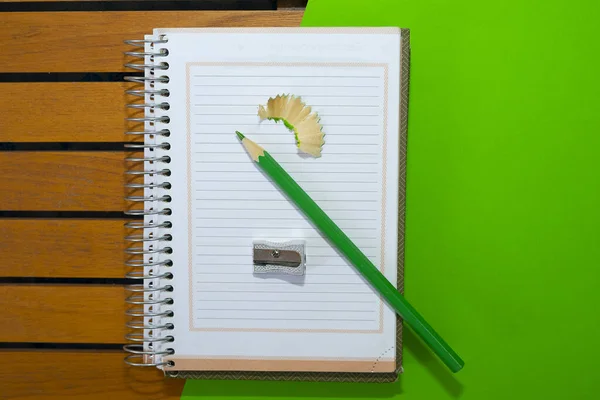 Notebook with green pencil and pencil sharpener. School supplies concept.