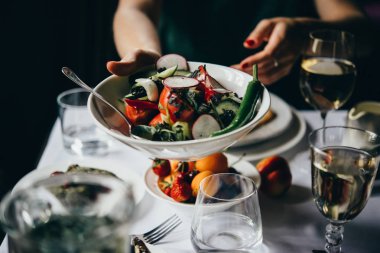 Eller salata bir kase içinde geçen bir partinin bir restoranda akşam yemeği sırasında hizmet.