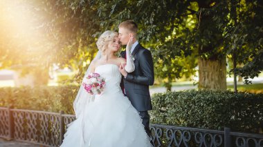 Damat gelini yeşil ağaçların arasında güneşin parlak ışınları öpüyor.