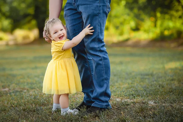 Sarı elbiseli küçük kız babasının pantolon hugs.
