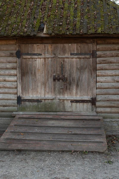 Oude ruwe houten schuur poort, landelijk gebouw voor vee, stal, magazijn, verticale schuur. Houten poort met metalen scharnieren en een slot — Stockfoto