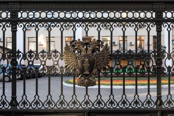 Moscú, Rusia - 01 de diciembre de 2019: Escudo de armas de metal de la Federación Rusa en la valla negra de la Fiscalía. Águila bicéfala sostiene un escudo con el texto Ley —  Fotos de Stock