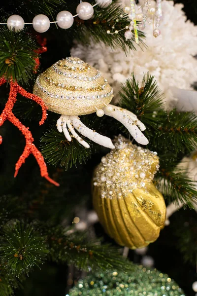Рождественская елка оформлена в морском стиле. Яркий блестящий золотой краб и раковина со стразами и жемчугом. Новогодняя открытка, зеленые ветви искусственной ели с кораллами — стоковое фото
