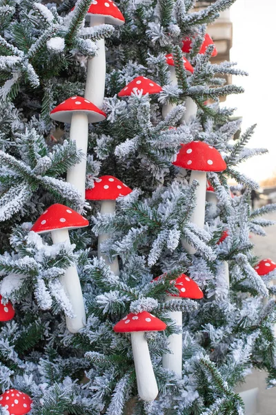 Yeni yıl dekorasyonu, dikey. Yapay ekolojik ladin ve sinek bakterisinde süslemeler. Dallarında kar ve mantar olan güzel Noel ağacı.