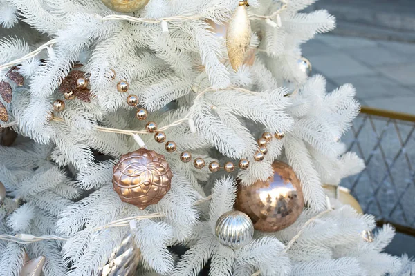 Décorations de jouets dorés sur un sapin de Noël artificiel blanc. Perles Shao ornements suspendus sur les branches de sapin respectueux de l'environnement, nouvelle année fête fond conception — Photo