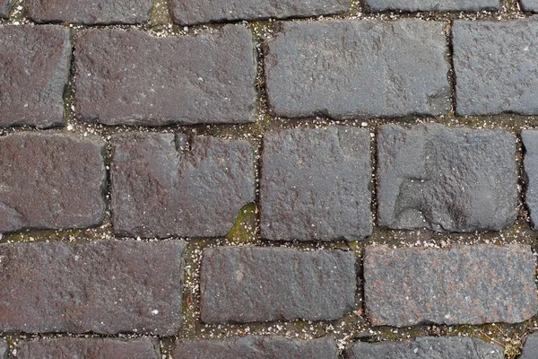 Текстура каменного тротуара с мелкими крошками ледяного града. Старые прочные булыжники дороги, каменный тротуар. Структура фона серого цвета — стоковое фото