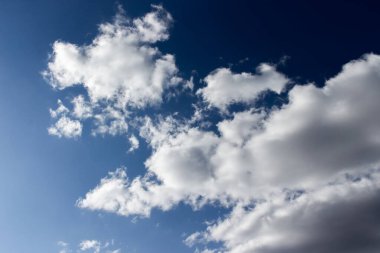 Beyaz bulutlu karanlık akşam gökyüzü. Alacakaranlık mavisi gökyüzü, kabarık kümülüs bulutları, cennet manzarası. Arkaplan duvar kâğıdı dokusu. Koyu mavi dramatik akşam gökyüzü