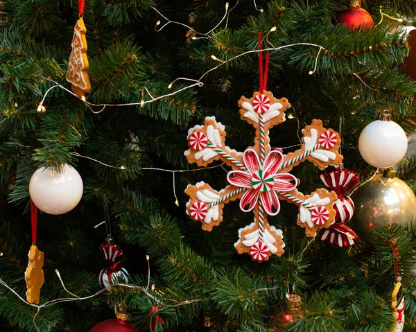 En stor snöflingkaka dekorerad med söt sockerglasyr. Julgran dekorerad med ingefära godis, kakor och bollar. Festlig bakgrund vykort tapet nytt år — Stockfoto