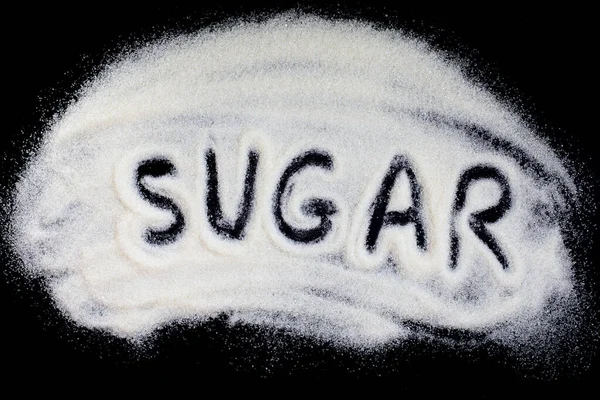 Ord socker hand bokstäver på en skylt med raffinerat vitt socker. Betsocker på en svart bakgrund — Stockfoto