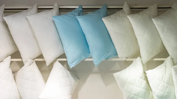 White blue lots of pillows on a store shelf. Bedding, comfortable quilted pillow for sleeping. Soft cotton natural fabric material