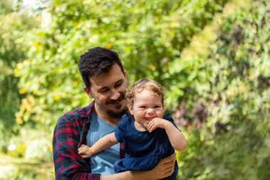 Babamla yürüyüşe çıkmış kıvırcık kız. Kızı dışarıda olan beyaz bir genç adam.