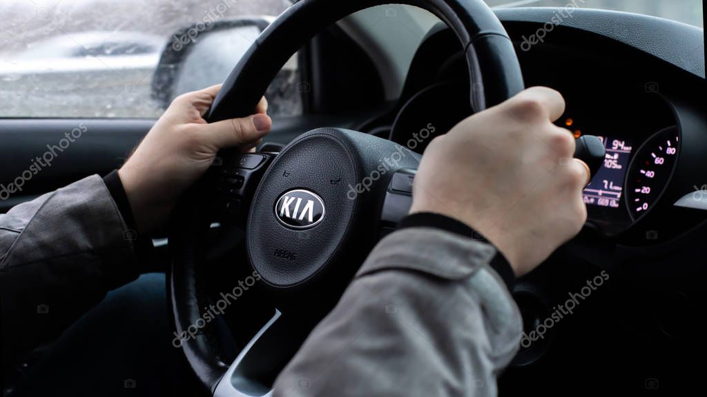 Moscow, Russia - January 2, 2020: Black steering wheel of a car with the KIA logo close-up. Hands of the driver behind the wheel of a South Korean SUV KIA Rio X-Line. Car driving