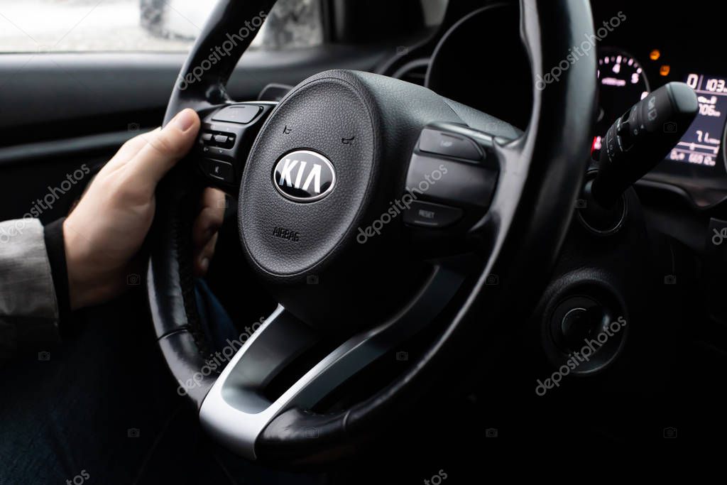 Moscow, Russia - January 2, 2020: Male hand on the steering wheel of a KIA Rio X-Line car. Black steering wheel with logo closeup. South Korean SUV car