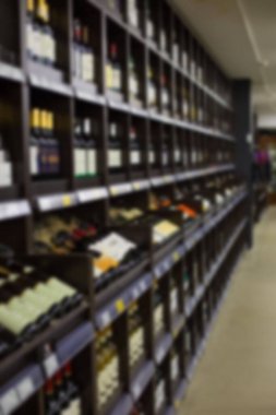 Defocus bulanık arkaplan, şarap şişeleriyle raflar dikey perspektif, şarap mahzeni, içki dükkanı, bir süpermarkette alkol bölümü, etiketli beyaz ve kırmızı şarap şişeleri depolama